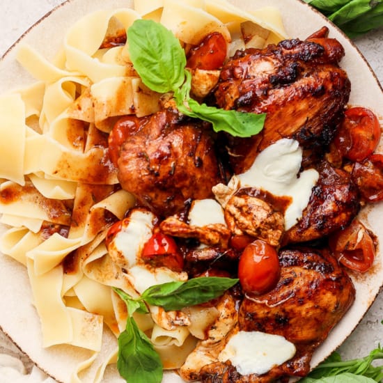 Grilled chicken with pasta and tomatoes on a plate.