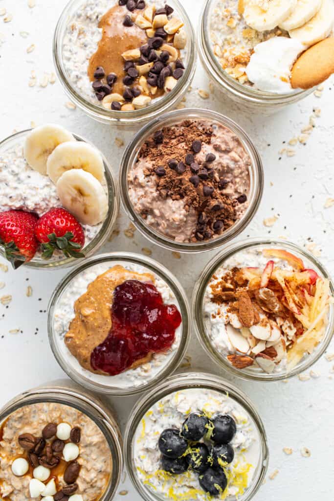 A group of jars filled with oatmeal, fruit, and nuts.