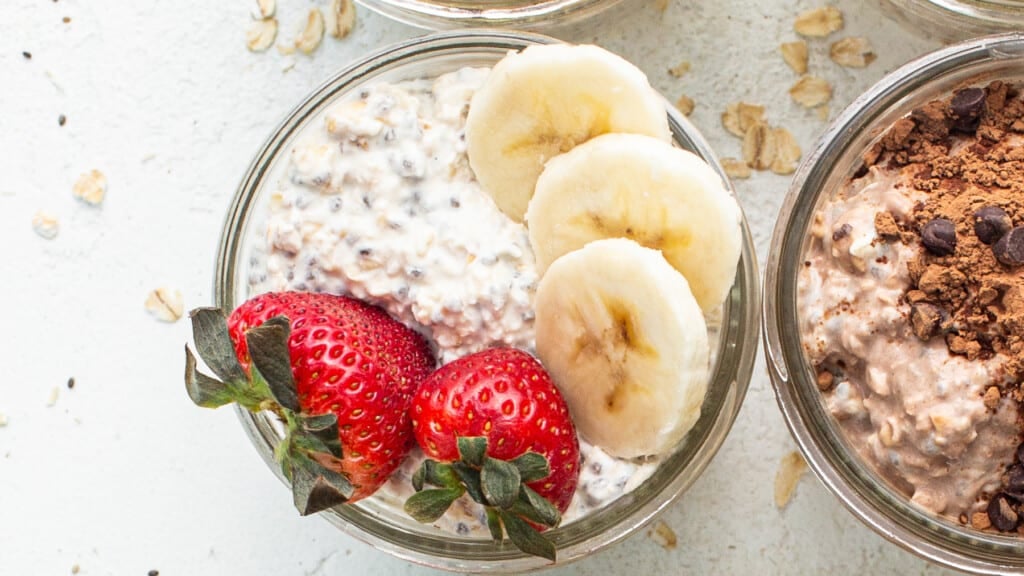 Three jars of oatmeal with chocolate chips, bananas and strawberries.