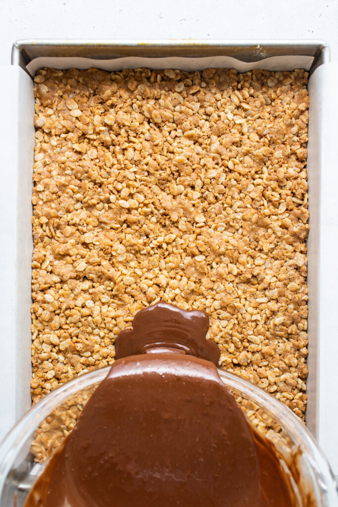 A c،colate sauce being poured over oats in a baking dish.