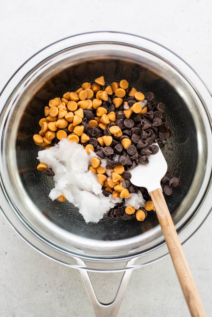 Chocolate chips in bowl with wooden spoon.