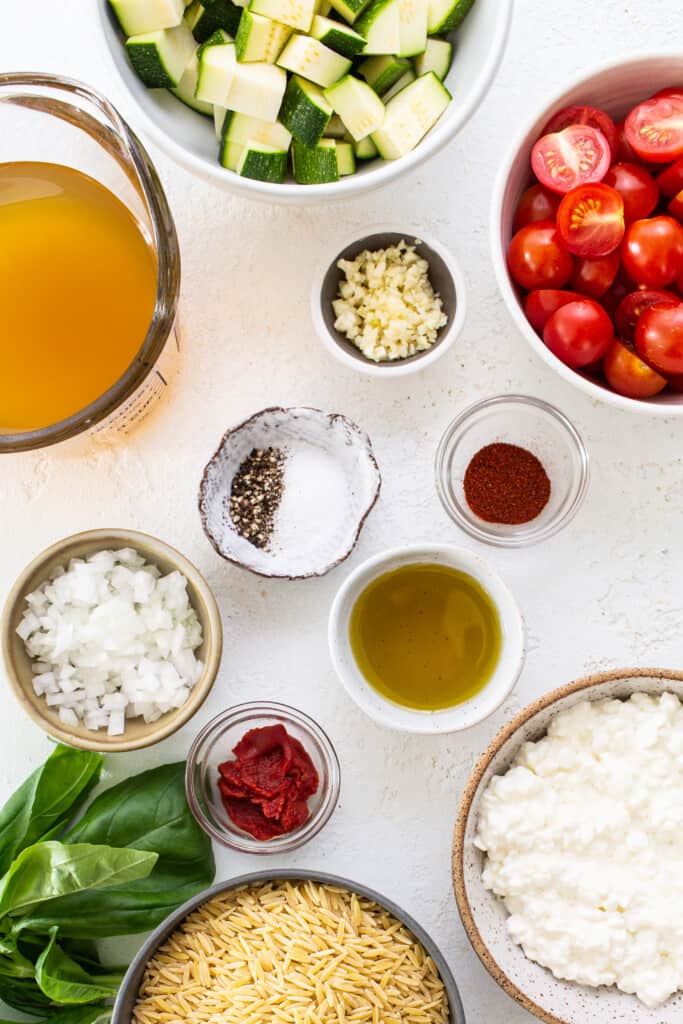Ingredients for a pasta dish including tomatoes, zuc،i, and basil.