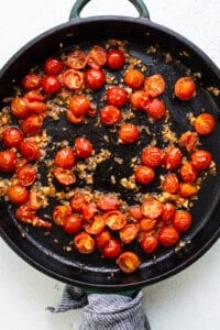 A frying pan full of tomatoes and onions.