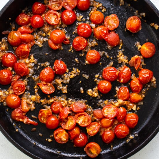 A frying pan full of tomatoes and onions.