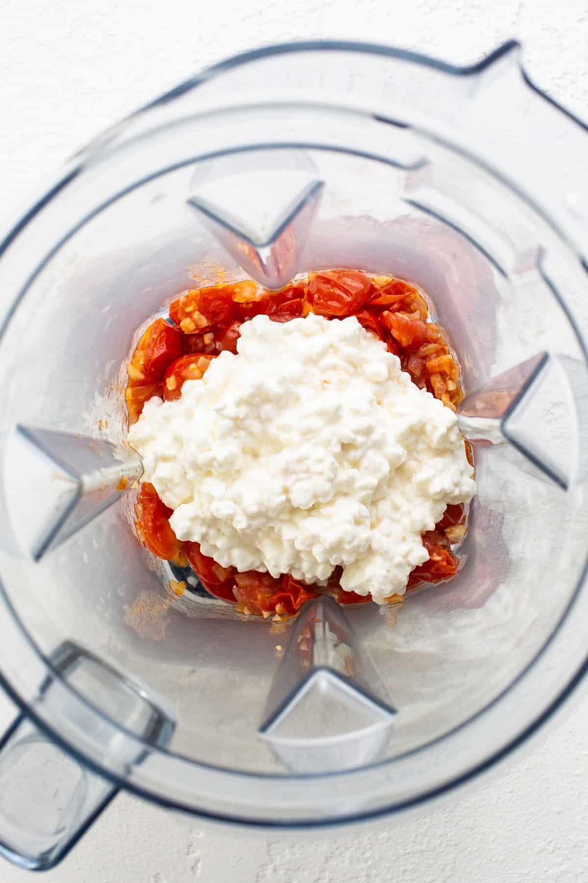 A blender filled with tomatoes and feta cheese.