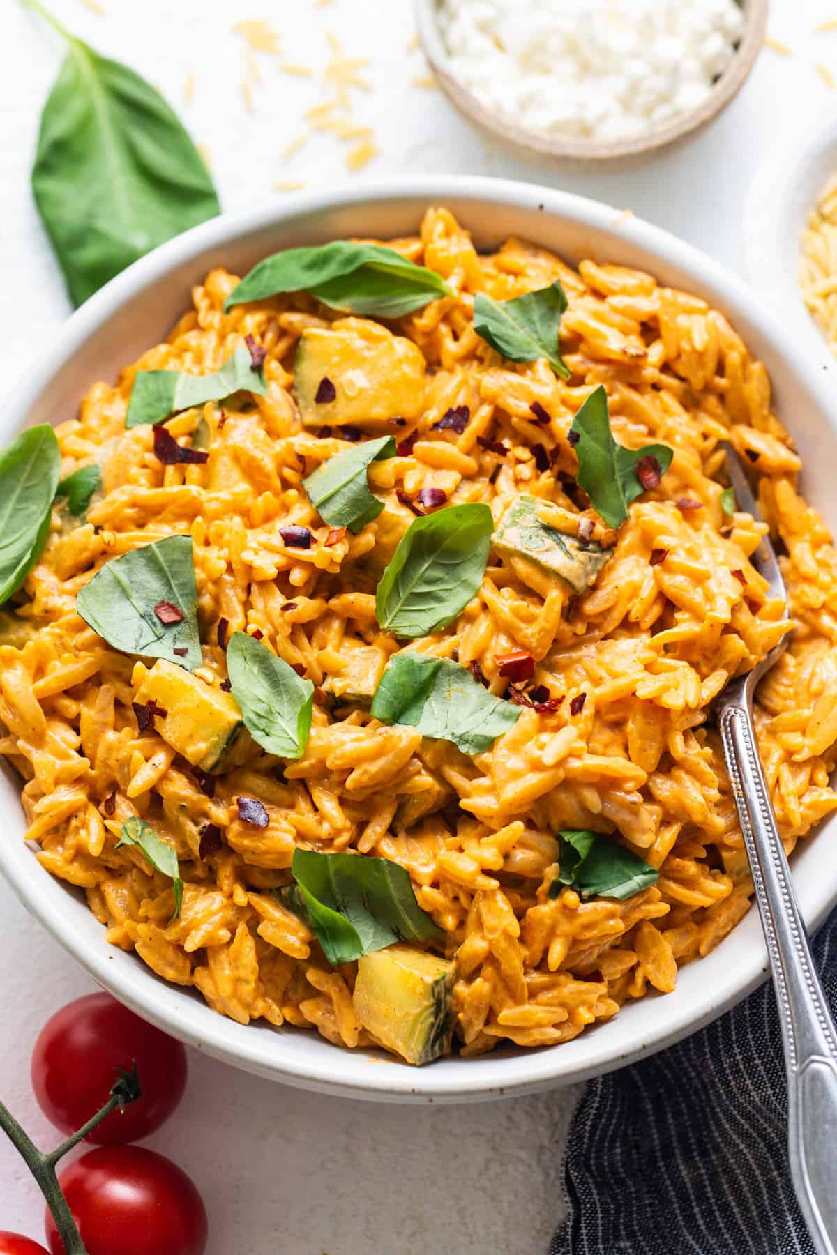 A bowl of rice with tomatoes and basil.