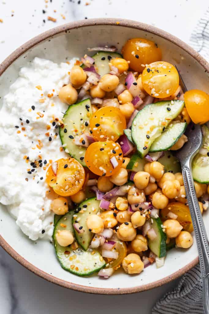 A bowl with chickpeas, cu،bers and yoghurt.