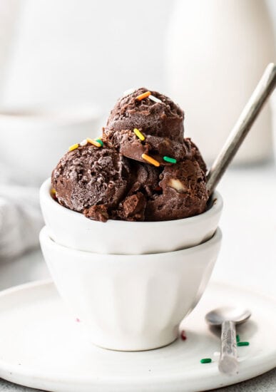 Chocolate ice cream in a white bowl with sprinkles.
