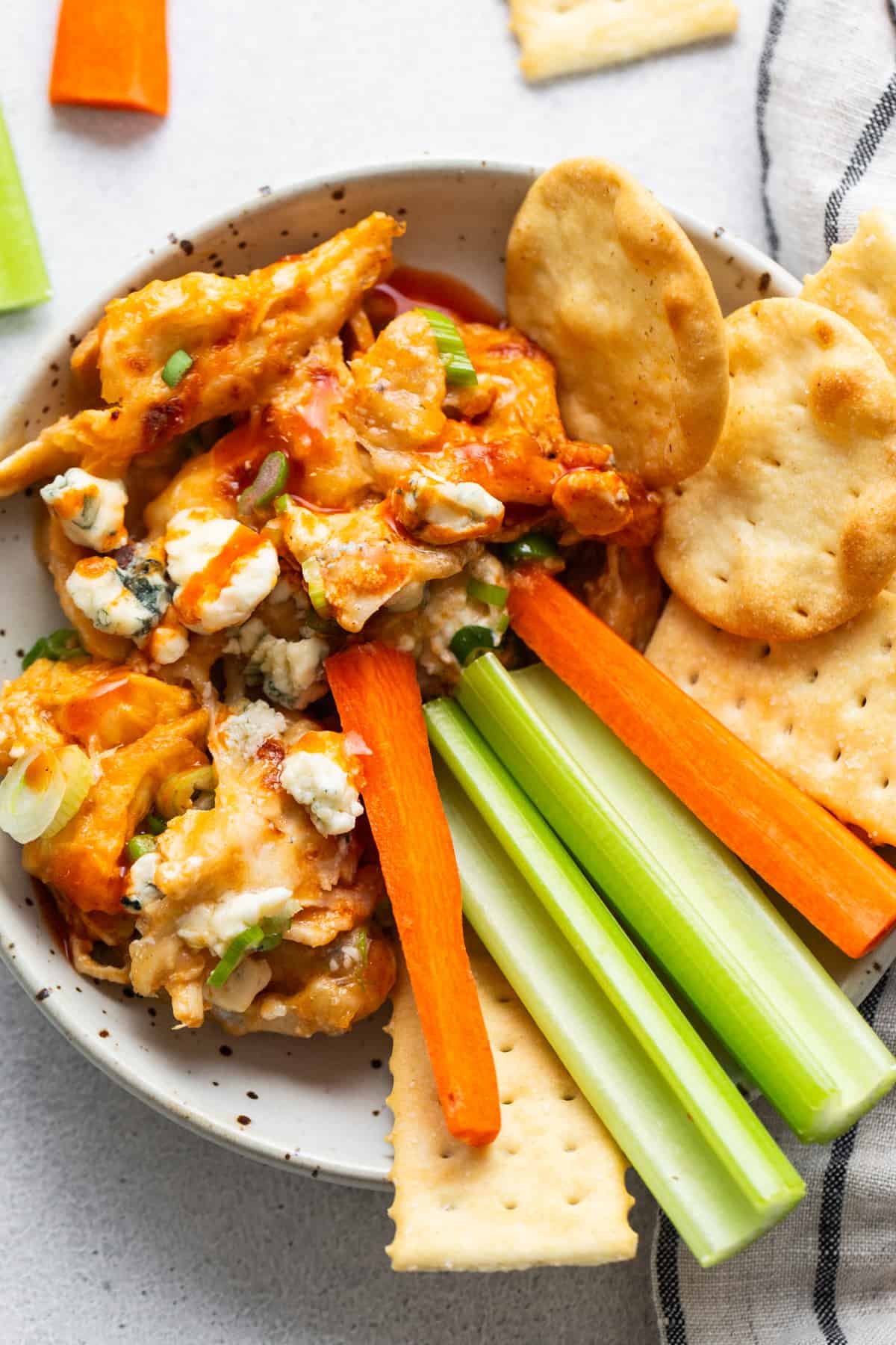 Buffalo wings dip in a bowl with celery, carrots and crackers.