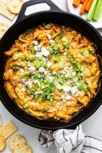 Buffalo chicken dip in a skillet with crackers.