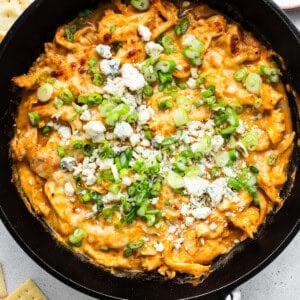 Buffalo chicken dip in a skillet with crackers.