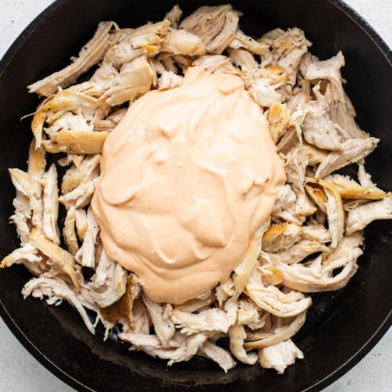 Chicken in a skillet with a sauce on top.