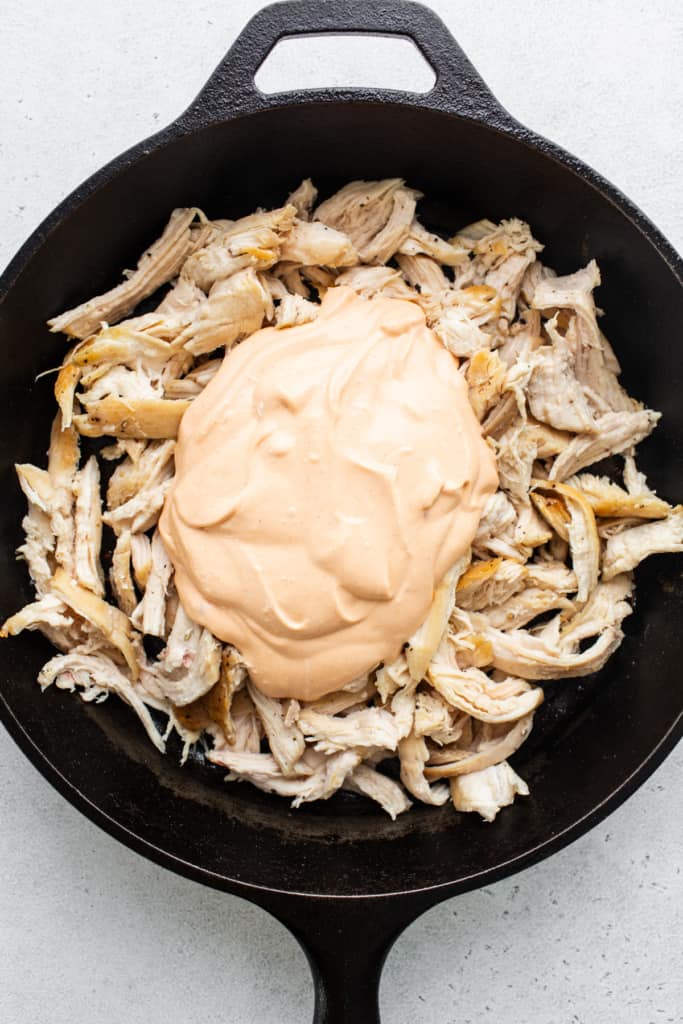 Chicken in a skillet with a sauce on top.