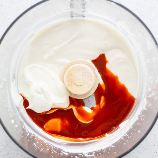 A food processor filled with sauce and whipped cream.
