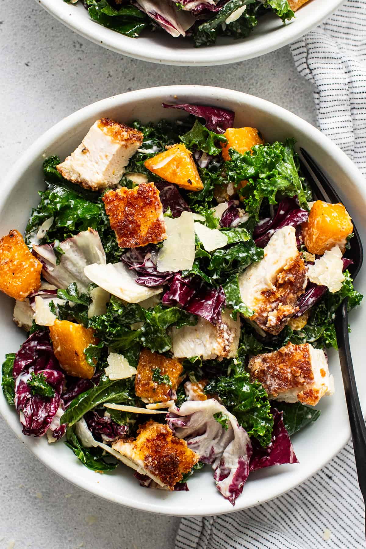 Two bowls of kale salad with chicken and parmesan.