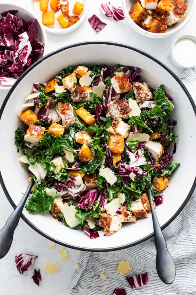 A bowl of kale salad with chicken and parmesan.