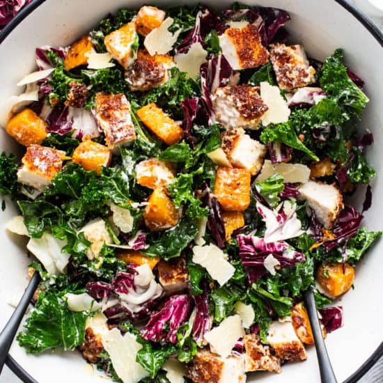 A bowl of kale salad with chicken and parmesan.