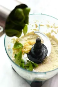 A vegan pasta dish topped with a medley of fresh greens and herbs, prepared using a food processor.