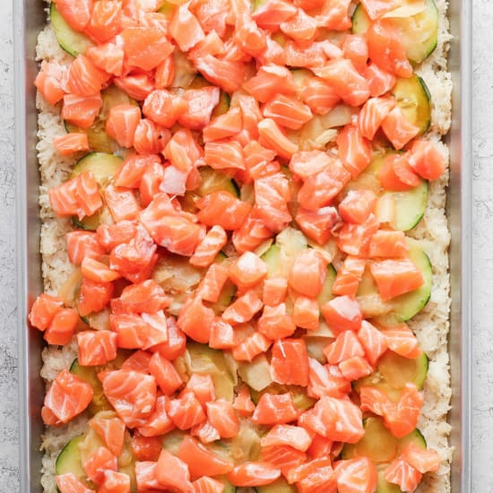 Salmon and cucumber pizza on a baking sheet.