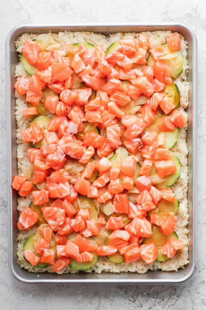 Salmon and cucumber pizza on a baking sheet.