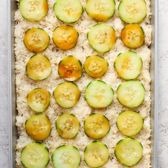 A baking pan filled with rice and cucumbers.