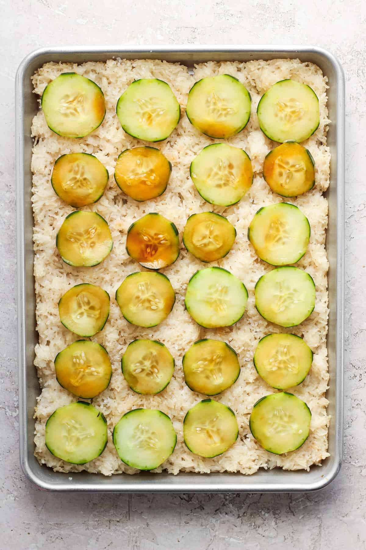 A baking pan filled with rice and cucumbers.