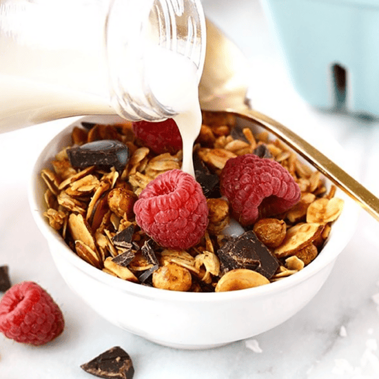 A bowl of chickpea granola with milk and raspberries.