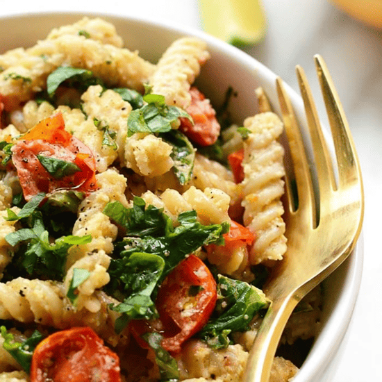 A vegan pasta salad with tomatoes and spinach.