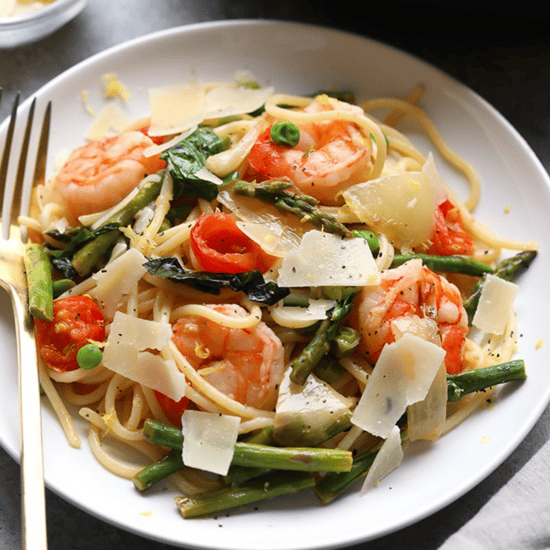 Shrimp scampi with asparagus served over a plate of pasta.