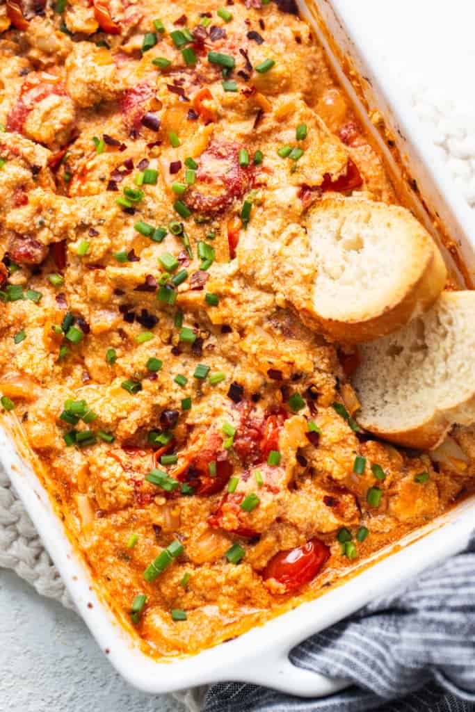 A casserole dish with chicken, tomatoes and bread.
