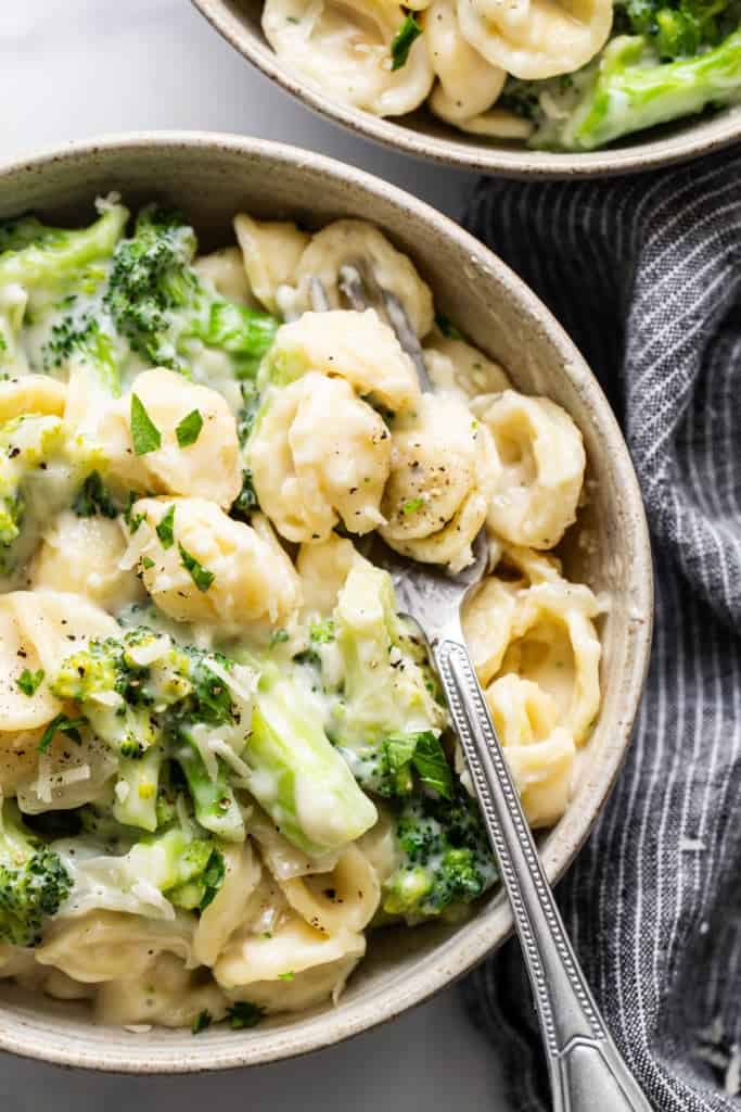 Two bowls of pasta with broccoli and cheese.
