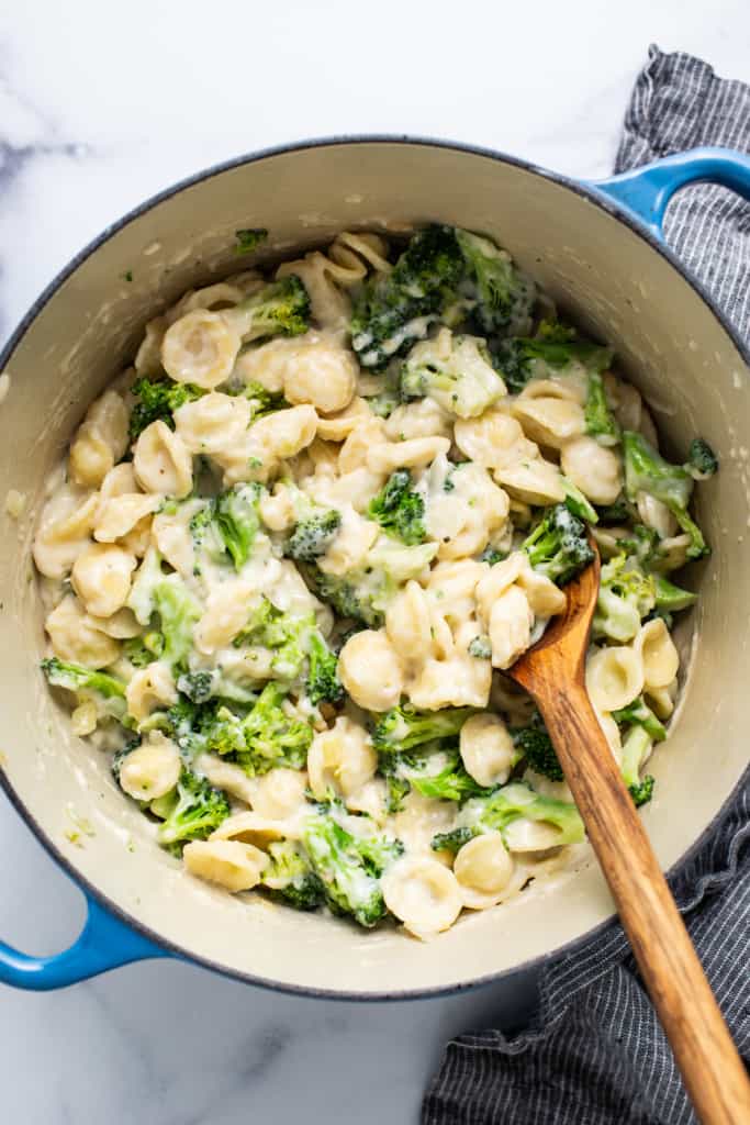 A pot of pasta with broccoli and cheese in it.