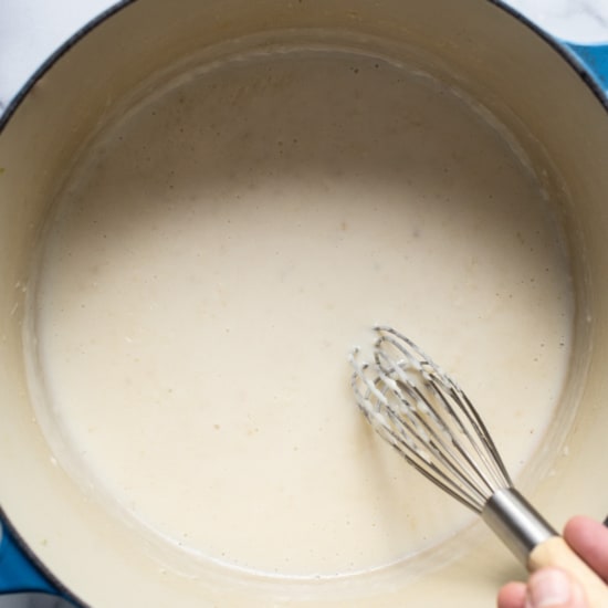 A person whisking a liquid in a pan.