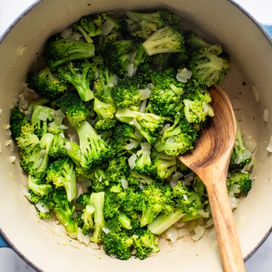 Broccoli in a blue pot with a wooden spoon.