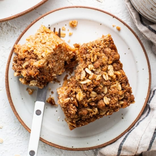 A slice of oatmeal coffee cake on a plate with a fork.