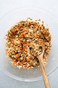 Oats in a bowl with a wooden spoon.