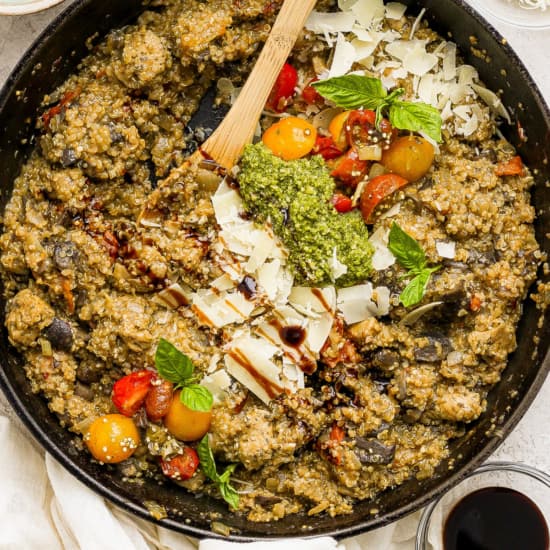 A skillet full of vegetables and herbs with a wooden spoon.