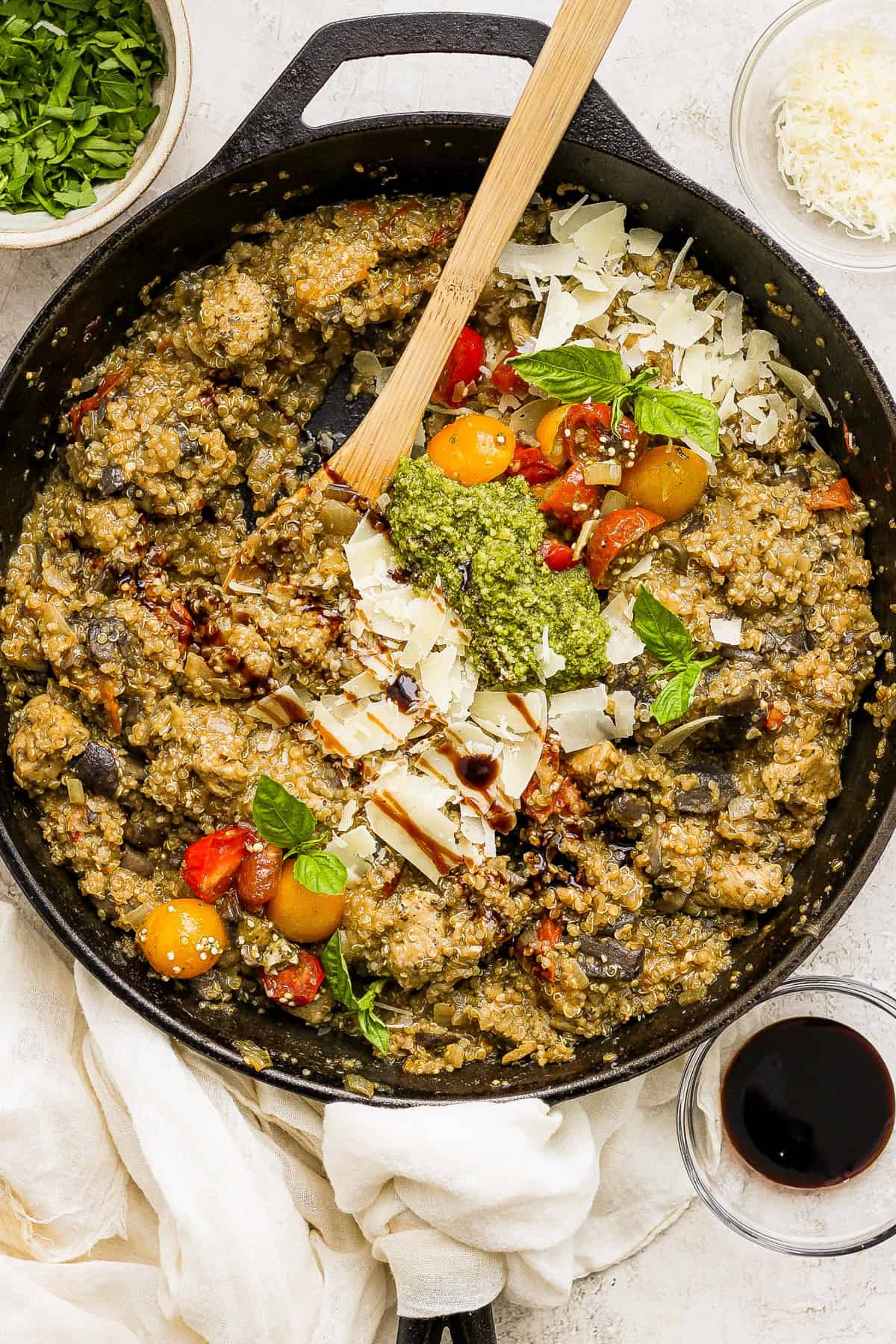 A skillet full of vegetables and herbs with a wooden spoon.