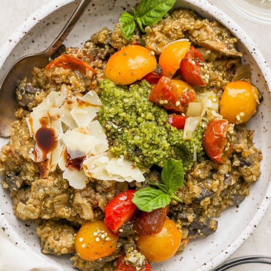 A bowl of risotto with tomatoes and pesto.