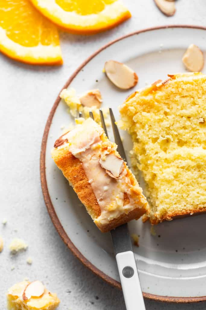 A slice of orange cake with almonds on a plate.