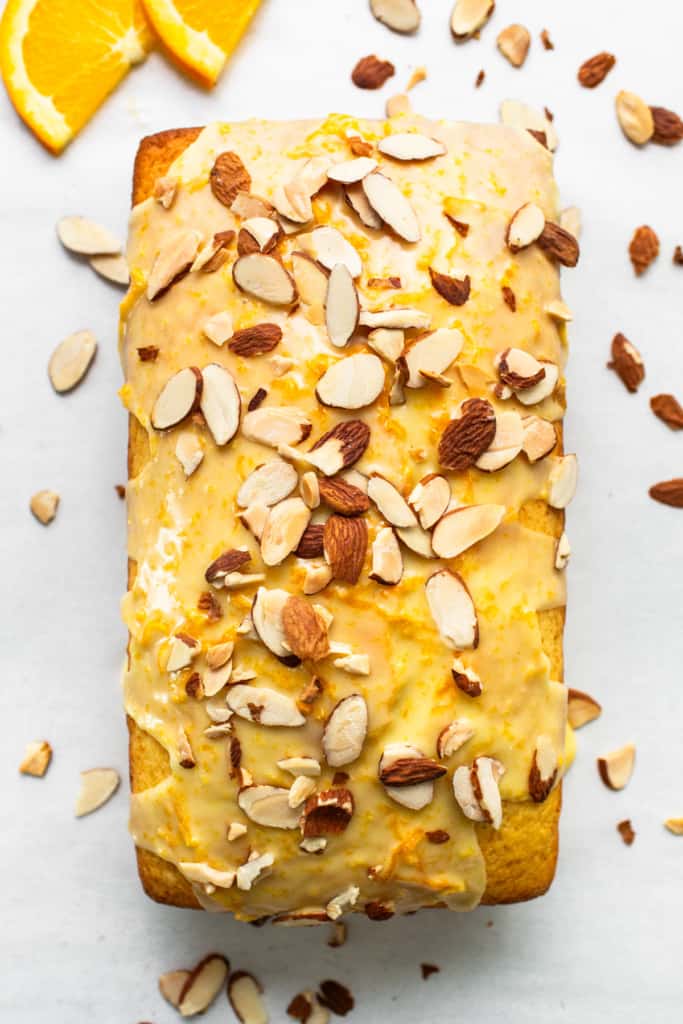 A loaf of orange bread with almonds and orange slices.