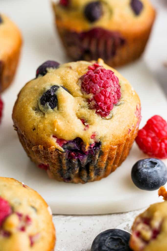 Berry muffins with blueberries and raspberries on a white plate.