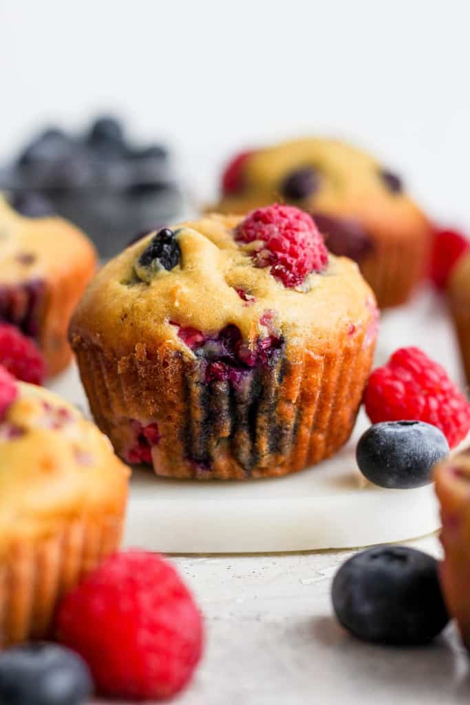 Berry muffins with blueberries and raspberries on a cutting board.