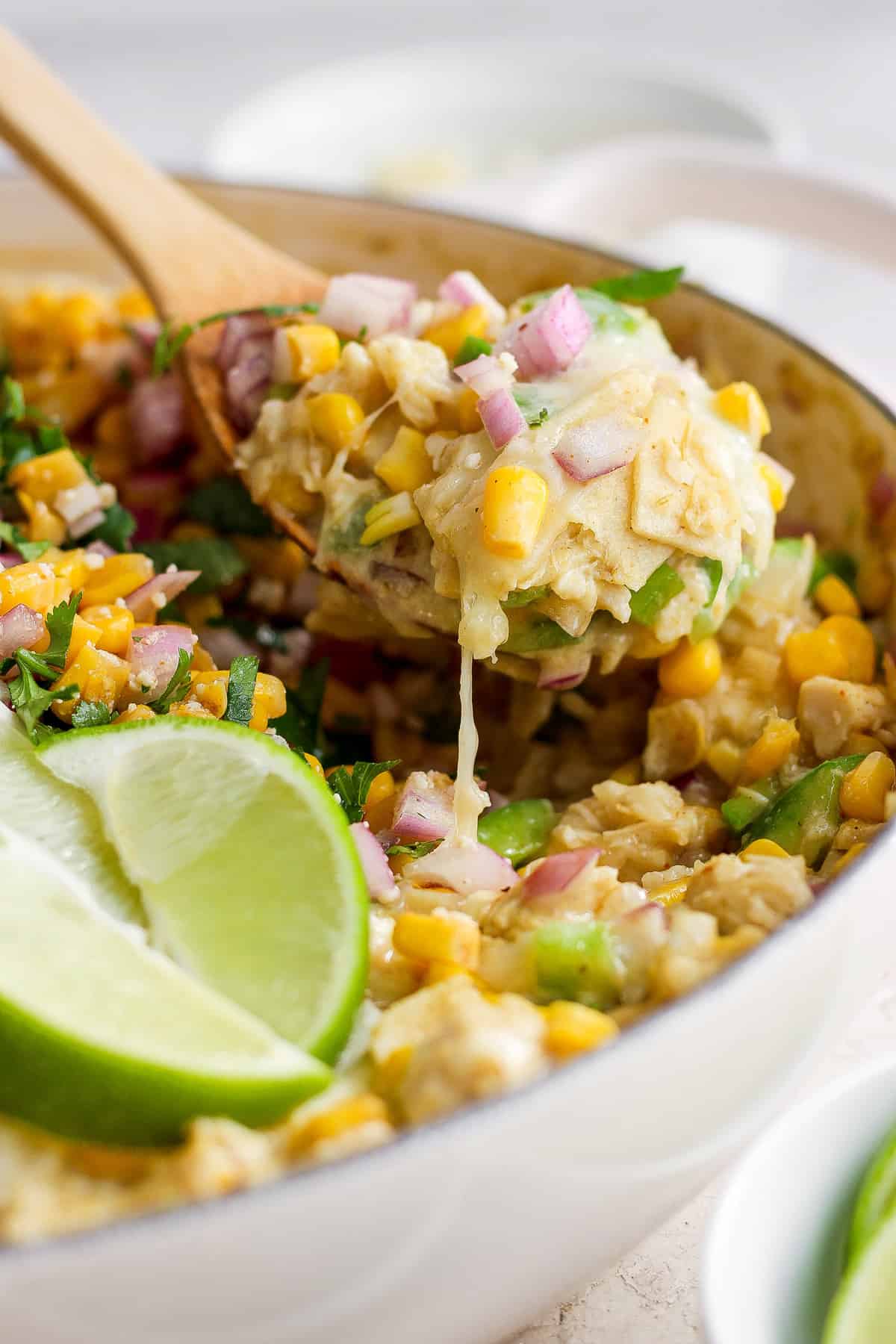 Mexican corn tortillas in a pan with a wooden spoon.