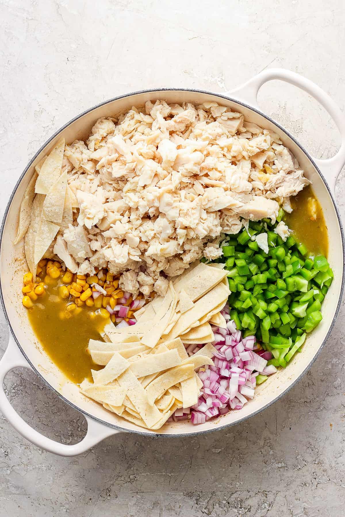 Mexican chicken enchiladas in a pan with corn and peas.