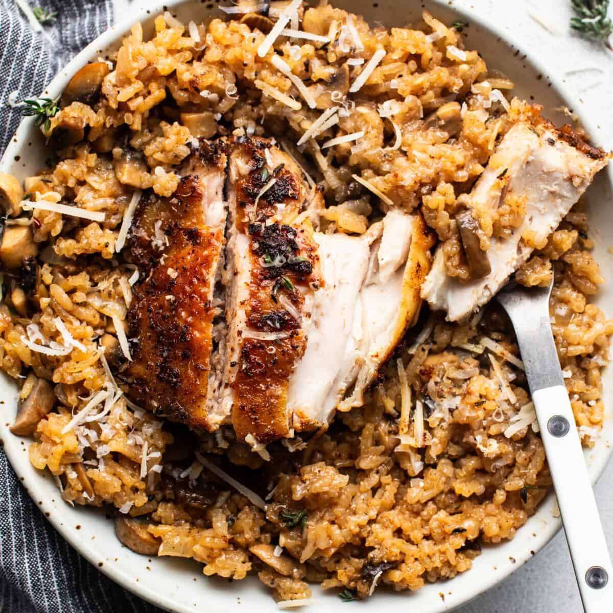 A bowl of rice with chicken and mushrooms.