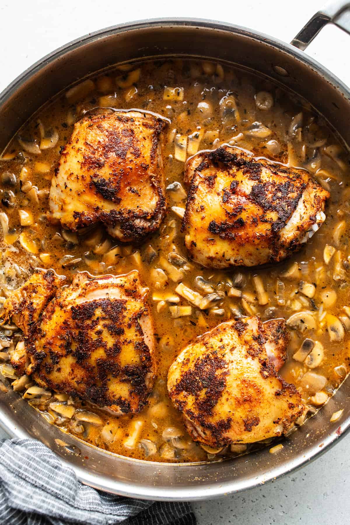 Chicken breasts in a pan with mushrooms and tomatoes.