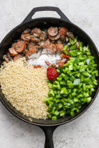 A frying pan with rice, mushrooms and green peppers.