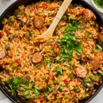 Sausage and rice in a skillet with a wooden spoon.