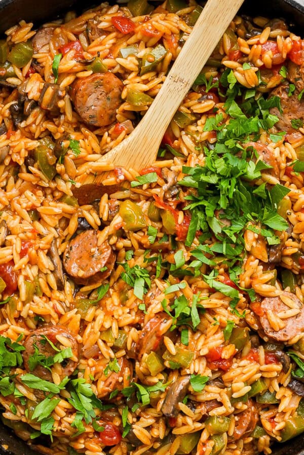 Sausage and rice in a skillet with a wooden spoon.